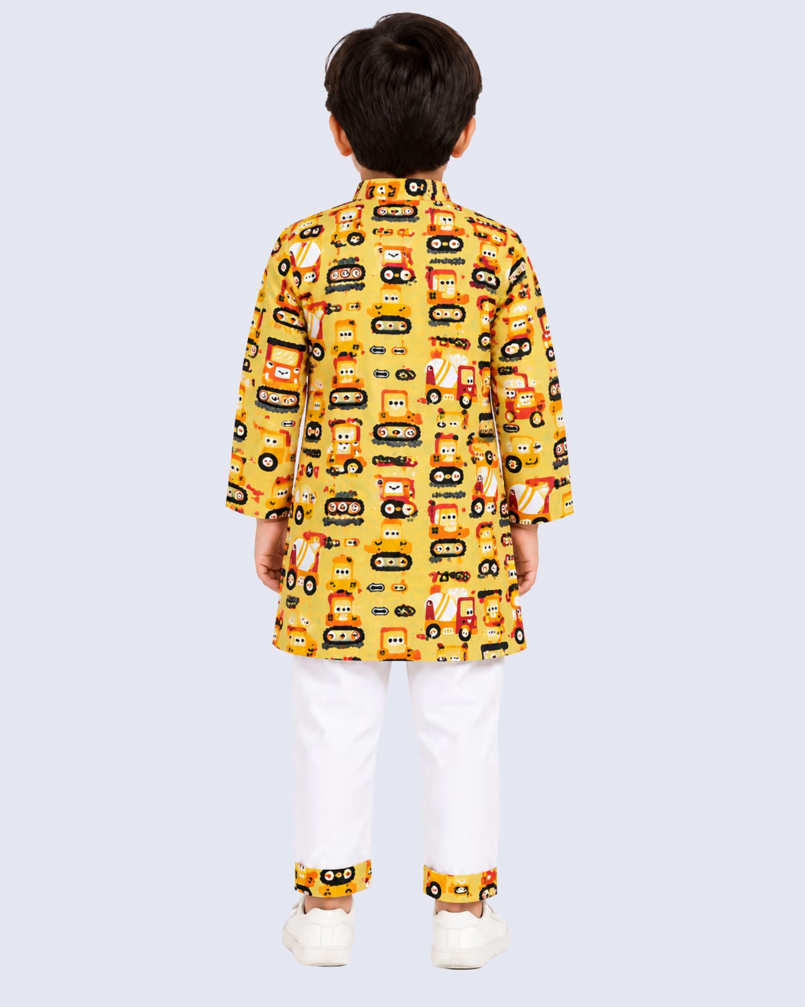 A child viewed from the back wearing a yellow long-sleeve kurta with an all-over cartoon bus pattern, paired with white trousers and white shoes, against a light gray studio background.